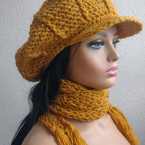 May include: A mustard yellow crocheted hat with a brim and matching scarf with long tassels.