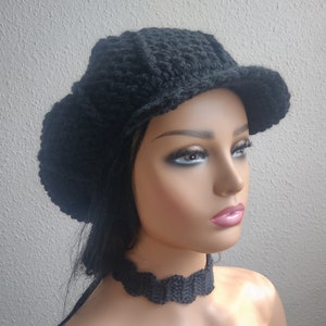 May include: A black crocheted beanie with a wide brim and a matching black crocheted choker.