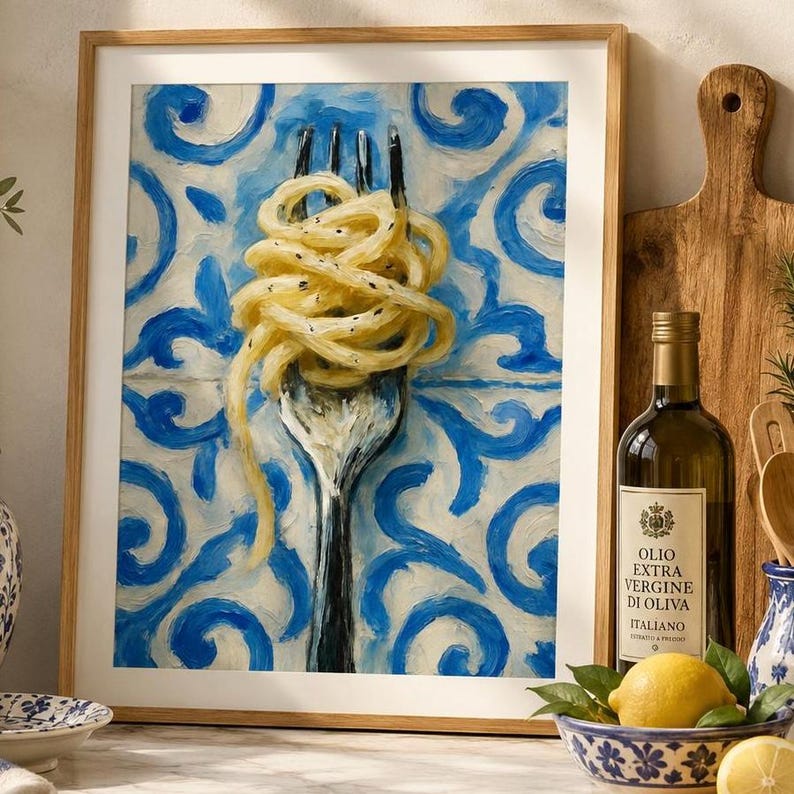 May include: A framed painting depicting a silver fork twirled with spaghetti noodles against a blue and white swirling tile pattern background. The artwork is displayed next to a bottle of olive oil and a bowl containing a yellow lemon.