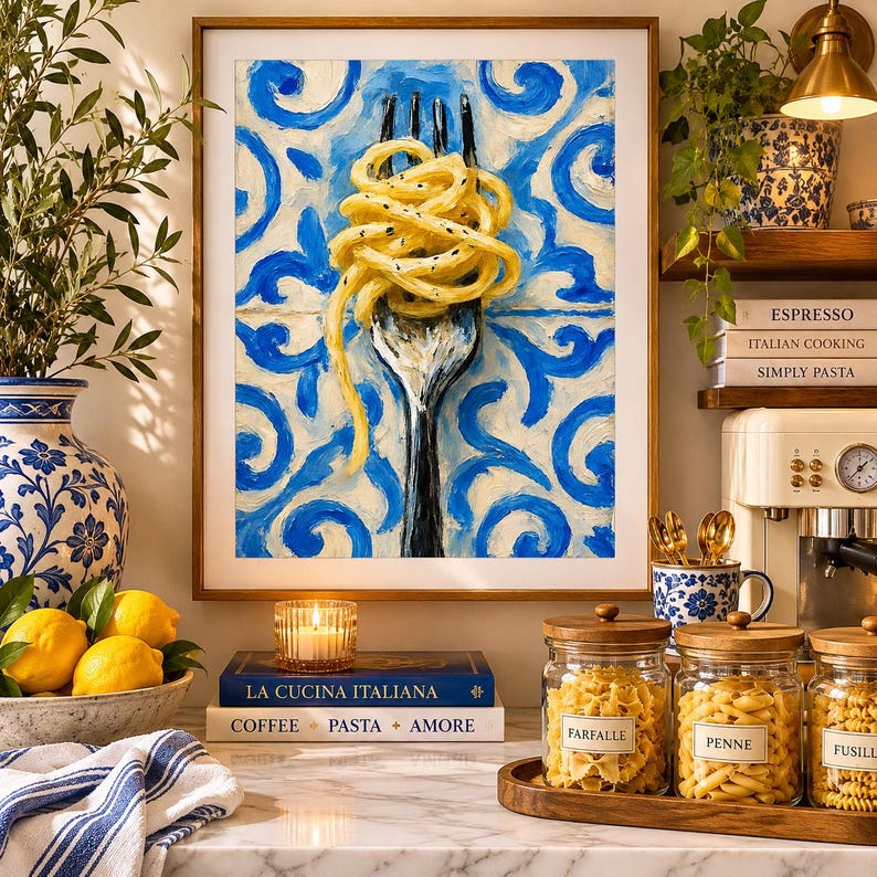 May include: A framed oil painting depicting a silver fork twirling yellow spaghetti against a blue and white patterned tile background. The artwork is displayed in a kitchen setting with glass jars of pasta, lemons, and books nearby.