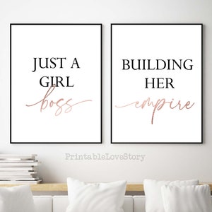 Puede incluir: Dos impresiones enmarcadas en negro con fondos blancos y texto dorado rosa. La impresi&oacute;n de la izquierda dice "Just a girl boss" y la impresi&oacute;n de la derecha dice "Building her empire".