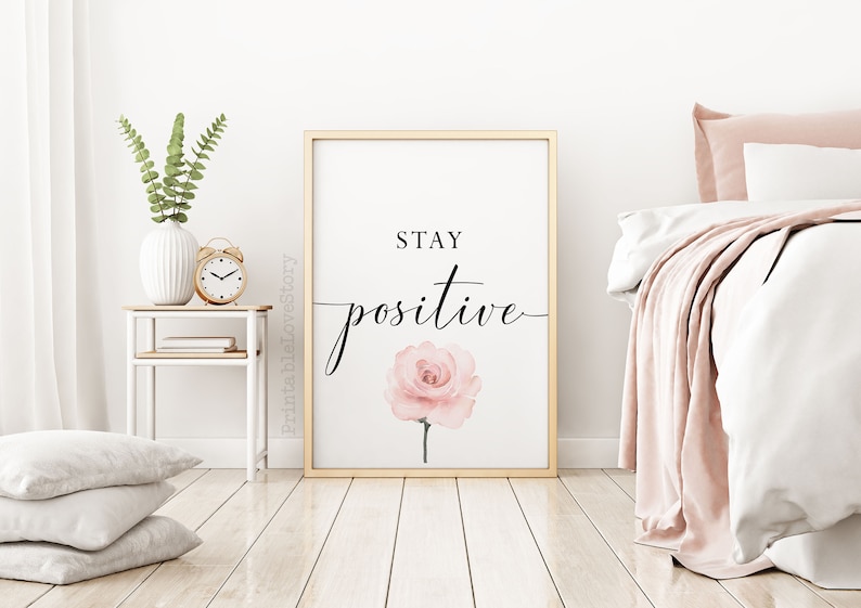 May include: A framed print with a gold frame and a white background. The print features a pink watercolor rose and the text "STAY POSITIVE" in black cursive font.