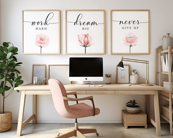 Peut inclure: Trois impressions encadrées avec des citations motivantes et des fleurs roses en aquarelle. Les impressions indiquent "travailler dur", "rêver grand" et "ne jamais abandonner". Les impressions sont accrochées à un mur blanc au-dessus d'un bureau en bois avec un fauteuil de bureau rose.