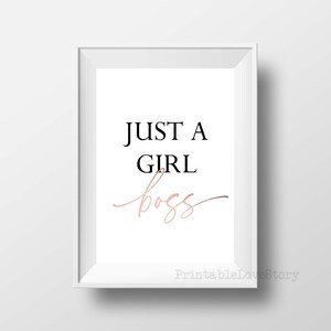 Puede incluir: Una impresi&oacute;n enmarcada en blanco con el texto "JUST A GIRL boss" en letras negras y doradas.