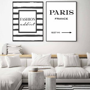Op de afbeelding: Twee zwart-witte ingelijste prints met een minimalistisch ontwerp. De linker print heeft zwart-witte strepen met de tekst "FASHION addict" in een zwarte doos. De rechter print heeft de tekst "PARIS FRANCE" met een pijl die naar rechts wijst en de tekst "1837 MI" eronder.