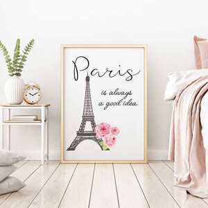 May include: A white framed print with a black and white illustration of the Eiffel Tower and pink flowers. The text "Paris is always a good idea" is written in black cursive font.