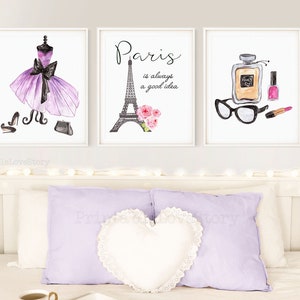May include: Three watercolor prints with a Parisian theme. The first print features a purple dress with a black bow and black shoes and purse. The second print features the Eiffel Tower with pink flowers and the text "Paris is always a good idea". The third print features a bottle of perfume, a pair of glasses, and a pink nail polish bottle and lipstick.
