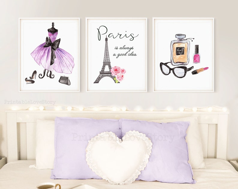 May include: Three watercolor prints with a Parisian theme. The first print features a purple dress with a black bow and black shoes and purse. The second print features the Eiffel Tower with pink flowers and the text "Paris is always a good idea". The third print features a bottle of perfume, a pair of glasses, and a pink nail polish bottle and lipstick.