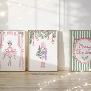 Puede incluir: Tres impresiones en acuarela enmarcadas con temática navideña. Las impresiones presentan una bailarina, un cascanueces y un saludo de "Feliz Navidad". La bailarina lleva un tutú rosa, el cascanueces un uniforme rosa y el saludo está en un círculo rosa.