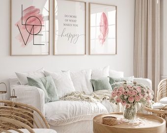 Puede incluir: Tres impresiones enmarcadas con diseños de acuarela rosa. La primera impresión presenta la palabra "LOVE" en negro con un círculo y líneas de acuarela rosa. La segunda impresión dice "Haz más de lo que te hace feliz". La tercera impresión presenta una pluma de acuarela rosa.
