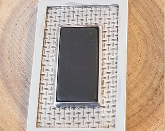 May include: A silver pendant featuring a black stone set within a square frame. The frame has a textured design.