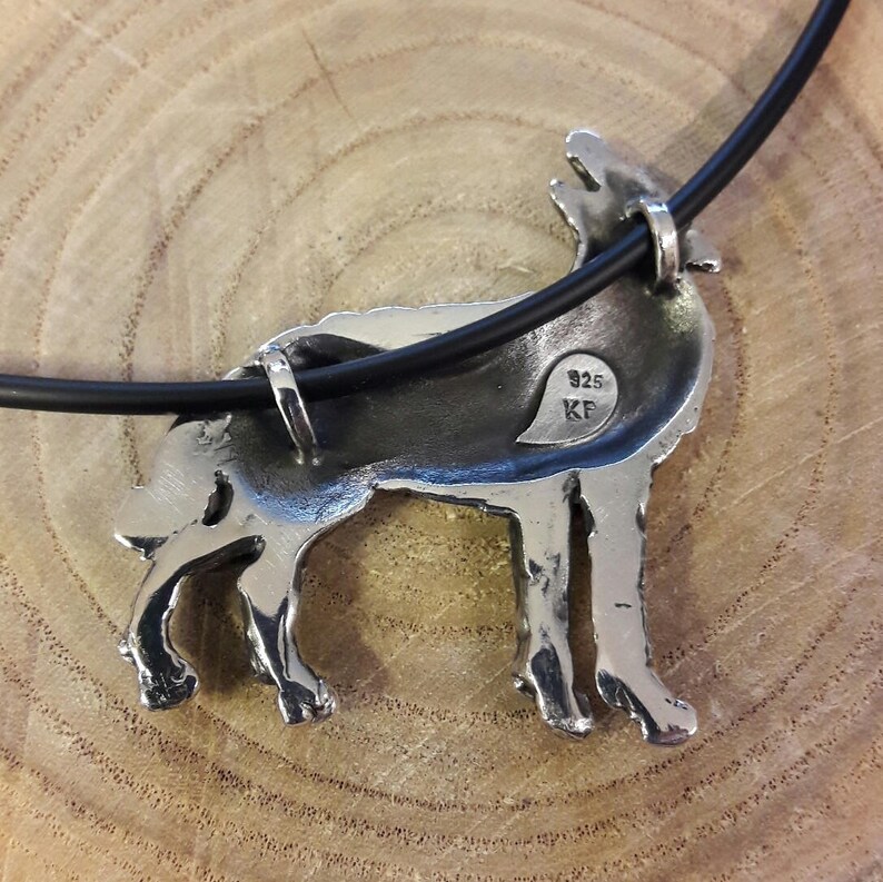 May include: Silver wolf pendant necklace with a black cord. The pendant is detailed and has the inscription "925 KF" on the back.