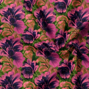 May include: A fabric featuring a repeating floral pattern with large, stylized blossoms in shades of vibrant magenta and deep navy blue. The background consists of a textured, mottled green surface that creates a contrast with the floral design.
