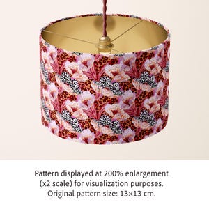 May include: A cylindrical lampshade featuring a vibrant pattern of pink and white flowers layered over a brown and black leopard print. The interior of the shade is metallic gold. A brown braided cord hangs from the top center. Pattern size: 5.1x5.1 inches.