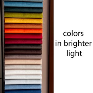 Peut inclure: Un nuancier de tissus pr&eacute;sentant une vari&eacute;t&eacute; de couleurs, notamment le violet, le gris, le bleu, le vert, le jaune, l'orange, le rouge, le marron, le beige, le blanc et le noir. Le texte "colors in brighter light" est visible sur le c&ocirc;t&eacute; droit de l'image.