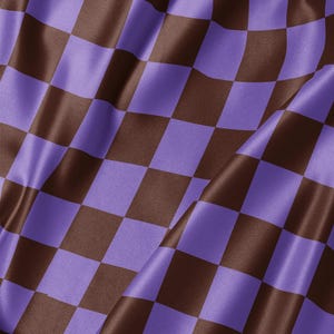 May include: A fabric featuring a repeating checkerboard pattern in alternating shades of dark brown and light purple. The material has a smooth, slightly reflective surface with soft folds that create subtle shadows across the square design.