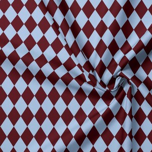 May include: A fabric featuring a repeating diamond pattern in alternating shades of deep maroon and light sky blue. The textile displays a consistent geometric harlequin design with soft folds creating natural shadows across the surface texture.