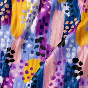 May include: A fabric featuring an abstract pattern of vertical brushstrokes and scattered dots in vibrant shades of yellow, purple, light pink, dark blue, and black. The design creates a textured, layered appearance across the surface of the material.