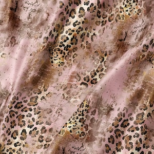 May include: A fabric featuring a soft pink background overlaid with a distressed brown and black leopard print pattern. The material displays a smooth, satin-like texture with visible folds and creases that create light and shadow across the surface.