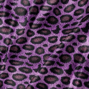May include: A fabric featuring a vibrant purple leopard print pattern. The design consists of dark black and deep maroon irregular spots scattered across a bright purple background, creating a textured appearance with visible folds in the material.