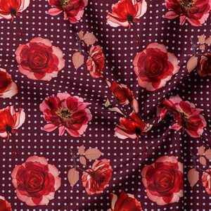 May include: A fabric featuring a deep burgundy background with a repeating pattern of small white polka dots and large, vibrant red roses. The floral design includes detailed petals and stems, creating a dense, colorful botanical print on textile.