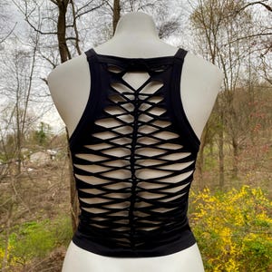 May include: Black tank top with a criss-cross design on the back. The design is made of cutouts in the fabric, creating a unique and stylish look.