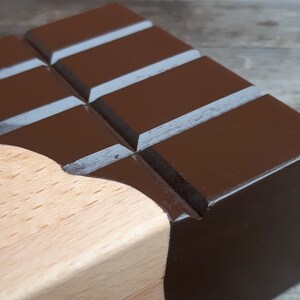 Puede incluir: Una caja de madera con forma de barra de chocolate con la parte superior pintada de marr&oacute;n y la base de madera natural.