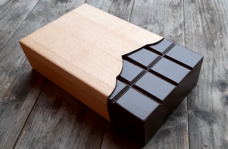Puede incluir: Una caja de madera con un dise&ntilde;o de barra de chocolate. La caja est&aacute; hecha de madera clara y tiene un dise&ntilde;o de barra de chocolate marr&oacute;n oscuro en la parte delantera. La barra de chocolate est&aacute; dividida en cuadrados y tiene un acabado brillante.