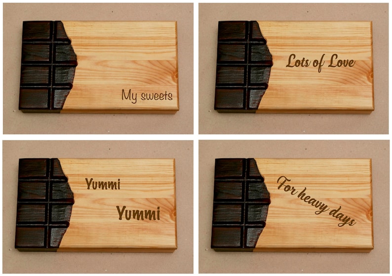 Puede incluir: Cuatro tablas de cortar de madera con un dise&ntilde;o de barra de chocolate. Las tablas est&aacute;n grabadas con el texto "My sweets", "Lots of Love", "Yummi Yummi" y "For heavy days".