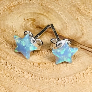 May include: A pair of silver star-shaped earrings with blue opal stones.