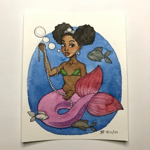 May include: Watercolor painting of a mermaid with dark skin, wearing a green seashell top and a pink tail. She holds a pearl necklace, surrounded by bubbles and fish. The background is a blue circle.