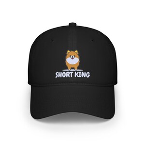 May include: Black baseball cap with a cartoon image of a small dog and the text "SHORT KING" embroidered in white.