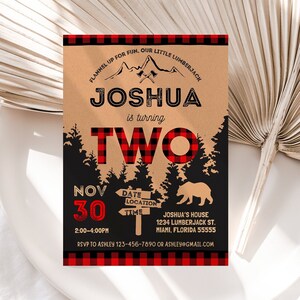 May include: A brown and red plaid birthday invitation for a boy turning two. The invitation features a woodland theme with a bear, trees, and a sign that says "Joshua is turning two". The date is November 30th, and the time is 2:00-4:00 PM. The location is Joshua's House, 1234 Lumberjack St., Miami, Florida 55555. RSVP to Ashley 123-456-7890 or ashley@gmail.com.