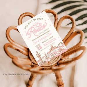 May include: A pink and brown invitation for a second birthday party with a western theme. The invitation says "This ain't my first Rodeo! It's my second! Saddle up partner, it's time to celebrate Laura turning two. Saturday October 28 from 2:00-4:00 p.m. 1234 First Rodeo Ave Miami Florida 55555 RSVP to Ashley 123-456-7890".