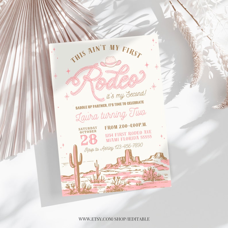 May include: Pink and gold invitation for a second birthday party with a western theme. The invitation says "This ain't my first Rodeo! It's my second! Saddle up partner, it's time to celebrate Laura turning two. From 2:00-4:00 p.m. Saturday, October 28, 1234 First Rodeo Ave, Miami Florida 55555. RSVP to Ashley 123-456-7890."