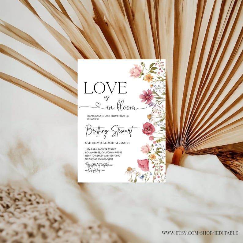 May include: A white invitation with a floral border and the text "Love is in bloom" in black script. The invitation is for a bridal shower honoring Brittany Stewart. The date and time of the shower are listed, along with the address and RSVP information.