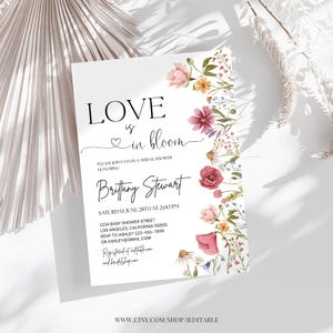 May include: A white bridal shower invitation with a floral design. The text reads "Love is in bloom" and includes the name "Brittany Stewart".