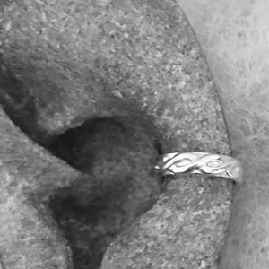 May include: A silver ear cuff with a braided design. The cuff is worn on the upper part of the ear.