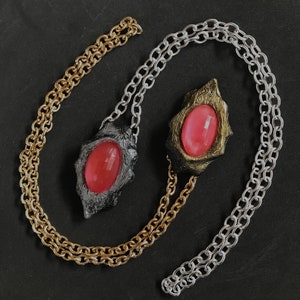 Pode incluir: Dois colares com pingentes de gemas cor-de-rosa. Um colar tem uma corrente de ouro e um pingente de ouro com uma gema cor-de-rosa. O outro colar tem uma corrente de prata e um pingente de prata com uma gema cor-de-rosa.