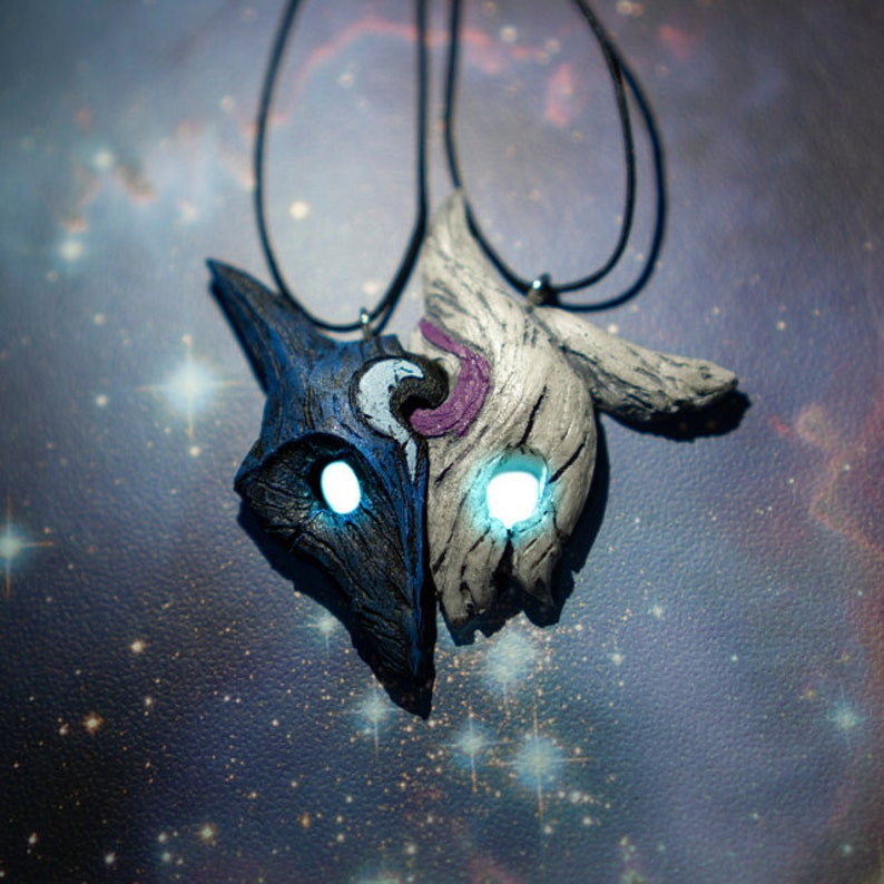 May include: A pair of necklaces with a blue and white wolf mask pendant. The masks are connected and have glowing eyes.