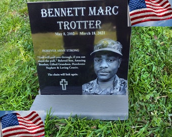 May include: Black granite headstone with a photo of a man in military uniform. The headstone reads "Bennett Marc Trotter, May 8, 2002 - March 18, 2021, Forever Army Strong." The inscription continues with a quote and a description of the deceased.