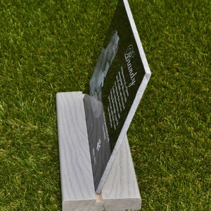 May include: Black granite pet memorial plaque with a paw print and the name "Brandy" engraved on it. The plaque is standing on a light gray wooden stand.