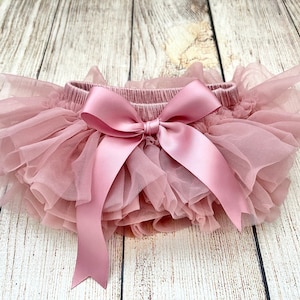 May include: A dusty rose tulle baby bloomers with a large satin bow in the center.