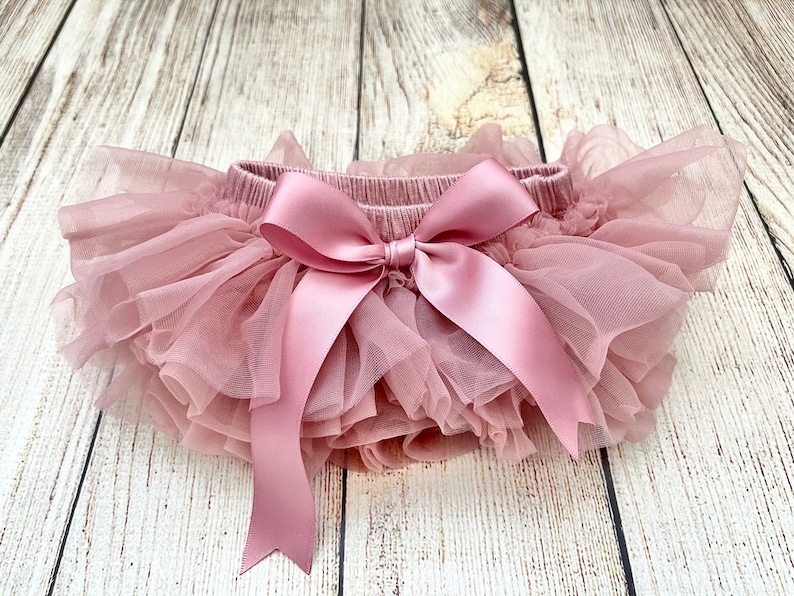 May include: A dusty rose tulle baby bloomers with a large satin bow in the center.