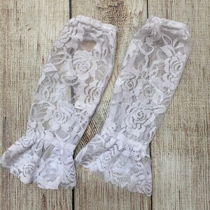May include: Two white lace arm warmers with a floral pattern and ruffled edges.