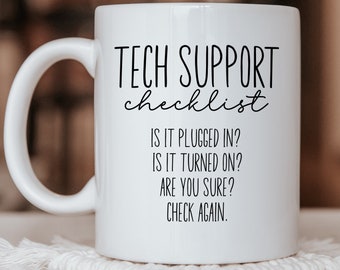 Peut inclure: Une tasse en céramique blanche avec une anse, portant l'inscription noire suivante : TECH SUPPORT checklist, IS IT PLUGGED IN?, IS IT TURNED ON?, ARE YOU SURE?, CHECK AGAIN. La tasse présente une finition lisse et un léger filet de vapeur.