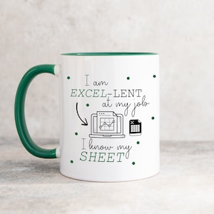 Może przedstawiać: Biały kubek do kawy z zielonym rantem i uchwytem. Kubek ma czarny wzór z napisem "Jestem EXCEL-LENT w swojej pracy" z rysunkiem laptopa z wykresem i ikoną arkusza kalkulacyjnego. Tekst kontynuuje "Znam swój ARKUSZ."
