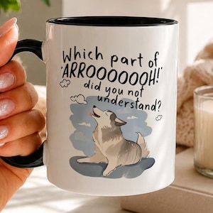 May include: A white ceramic mug with a black handle and interior rim. The mug features a graphic of a howling dog and the text: Which part of ARROOOOOOH! did you not understand? The design includes small cloud illustrations in a blue sky.