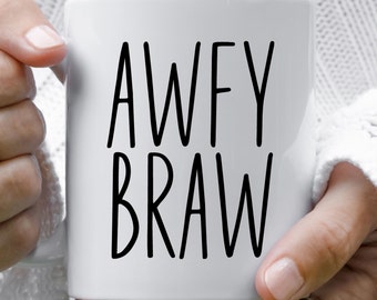 May include: A white ceramic mug featuring the black text AWFY BRAW printed in a tall, thin, sans-serif font. The mug has a smooth, cylindrical body with a handle on the side, designed for holding hot or cold beverages in a simple, clean style.