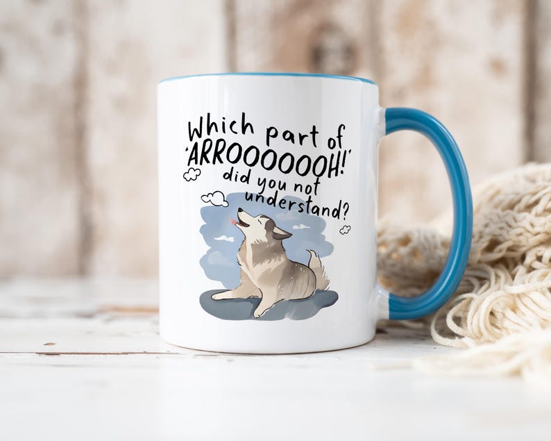 May include: A white ceramic mug with a blue handle and interior rim. The mug features a graphic of a howling dog and the black text: Which part of 'ARROOOOOOH!' did you not understand? The design includes small cloud icons around the text.